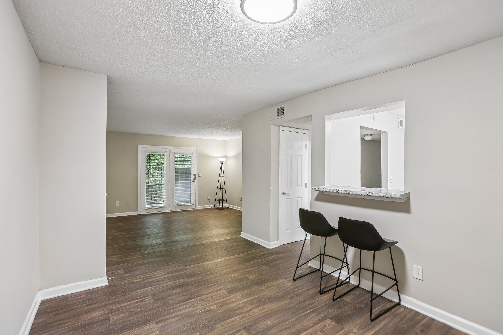 A room with a wooden floor and two black chairs.
